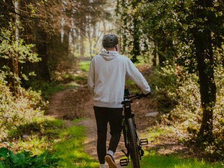Mann_mit_Fahrrad_im_Wald Ein entspannter Spaziergang mit dem Fahrrad durch den sonnendurchfluteten Wald – Naturgenuss pur an der Mosel.